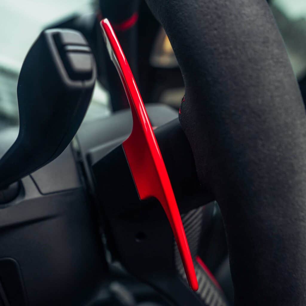 paddleshifters gloss red aluminium paddle shifters mounted in a BMW f30 showed from the side on an alcantara steering wheel