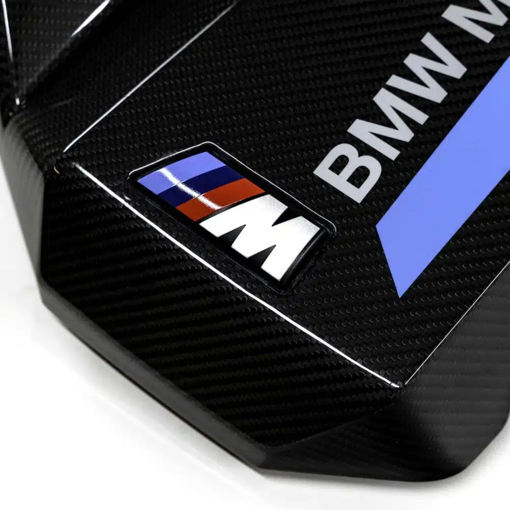 Close up shot of the OEM BMW Carbon fiber engine cover for S58 engines 11145B311A3 showing the M logo