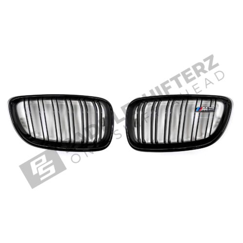A top down shot of the PaddleShifterz OEM BMW Gloss Black front grilles BMW F87 M2 51712355447 51712355448 laid down on a white background