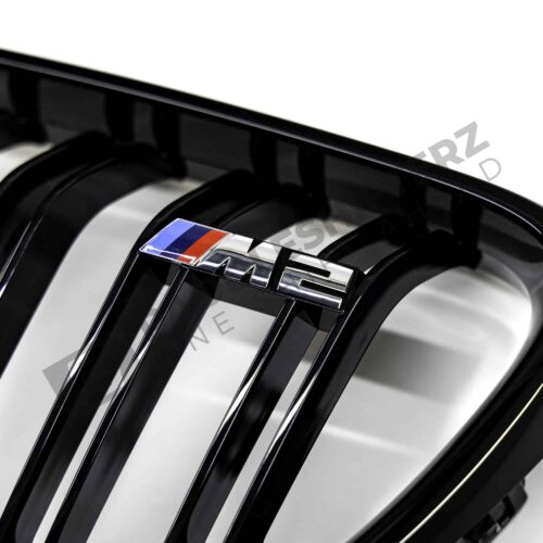 OEM BMW gloss black front grille for F87 M2 51712355448 right side close up shot of the M2 logo