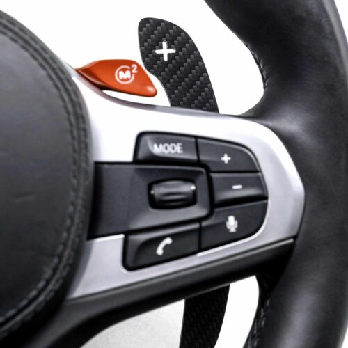 Magnetic structured carbon fiber paddle shifters fitted onto a G87 M2 steering wheel shown from the front