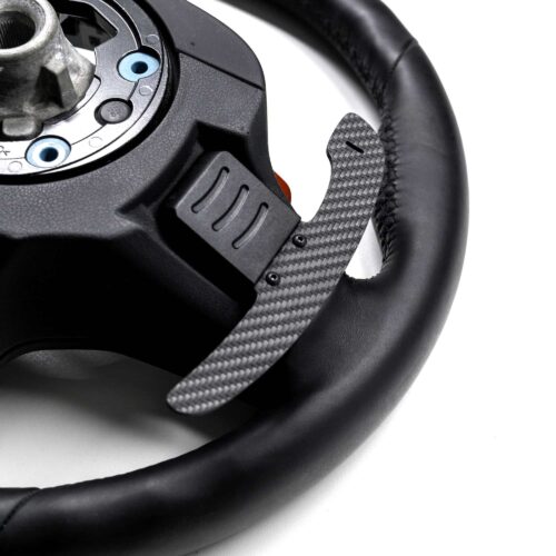 Structured carbon fiber paddle shifter left side shown on a leather steering wheel on a white background
